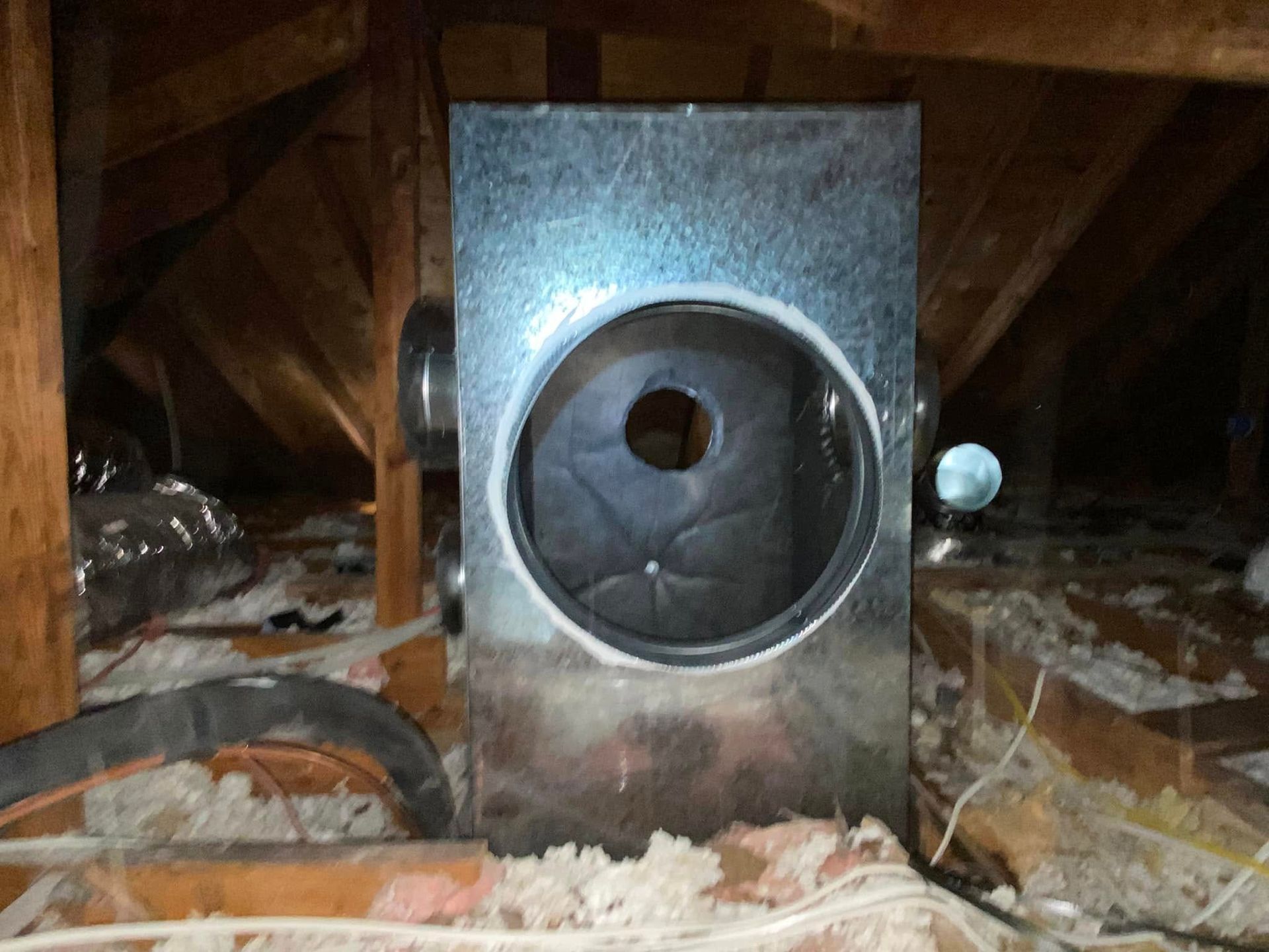 A metal box with a hole in the middle is in the attic.
