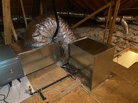 A metal pipe is hanging from the ceiling of an attic.
