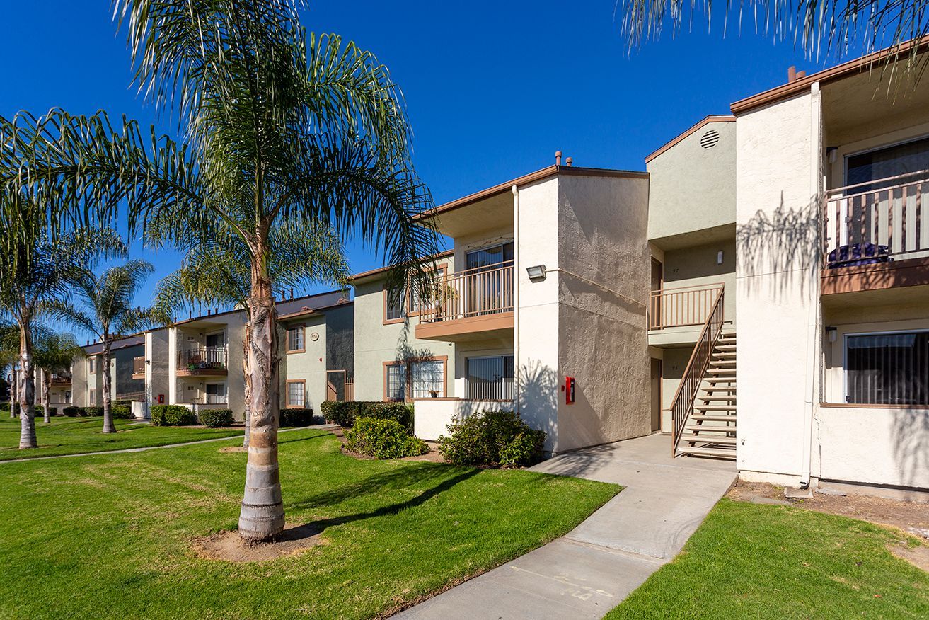 a row of apartment buildings with palm trees in front of them