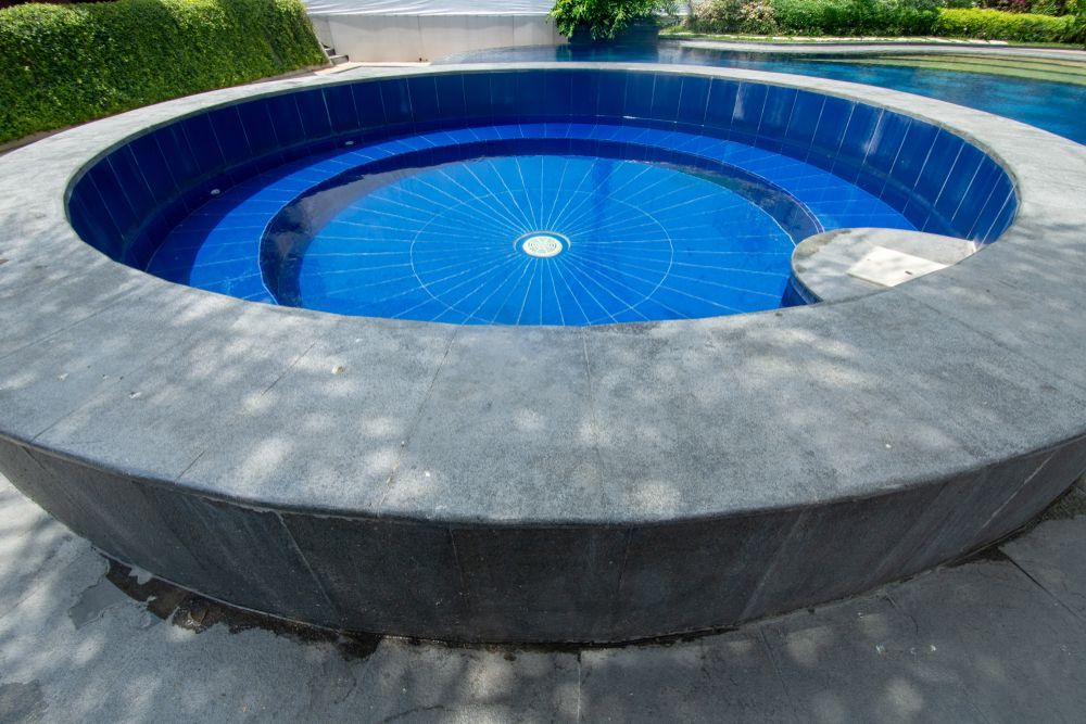 Round Swimming Pool With A Blue Tile Surrounding It — Beaches Pool Supplies in Kewarra Beach, QLD