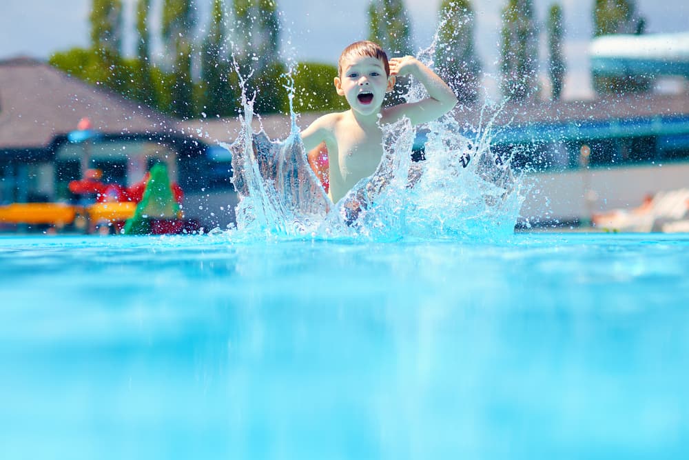 Young boy is jumping into a swimming pool — Pool Equipment Installation in Kewarra Beach QLD