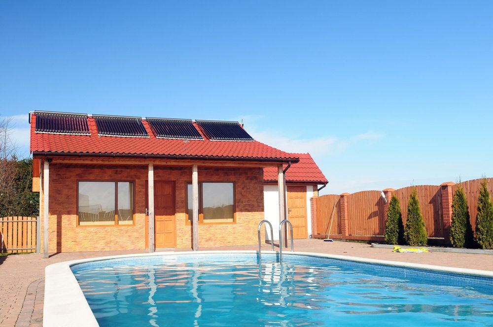 Swimming pool in front of a house with solar panels on the roof — Pool Shop in Brinsmead, QLD
