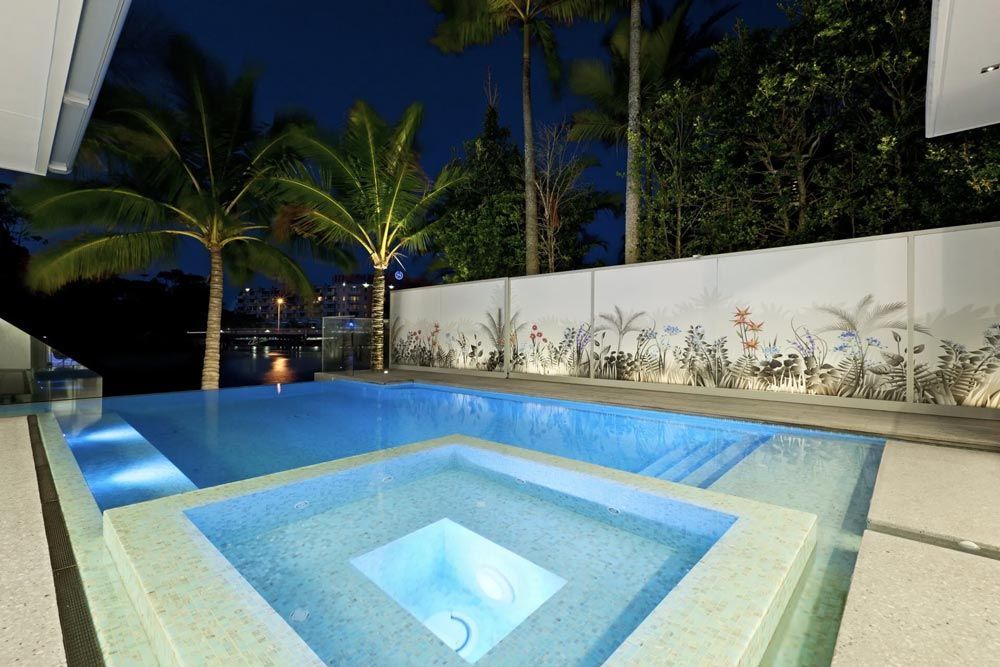 Swimming pool with a hot tub in the middle at night — Pool Equipment Installation in Kewarra Beach QLD