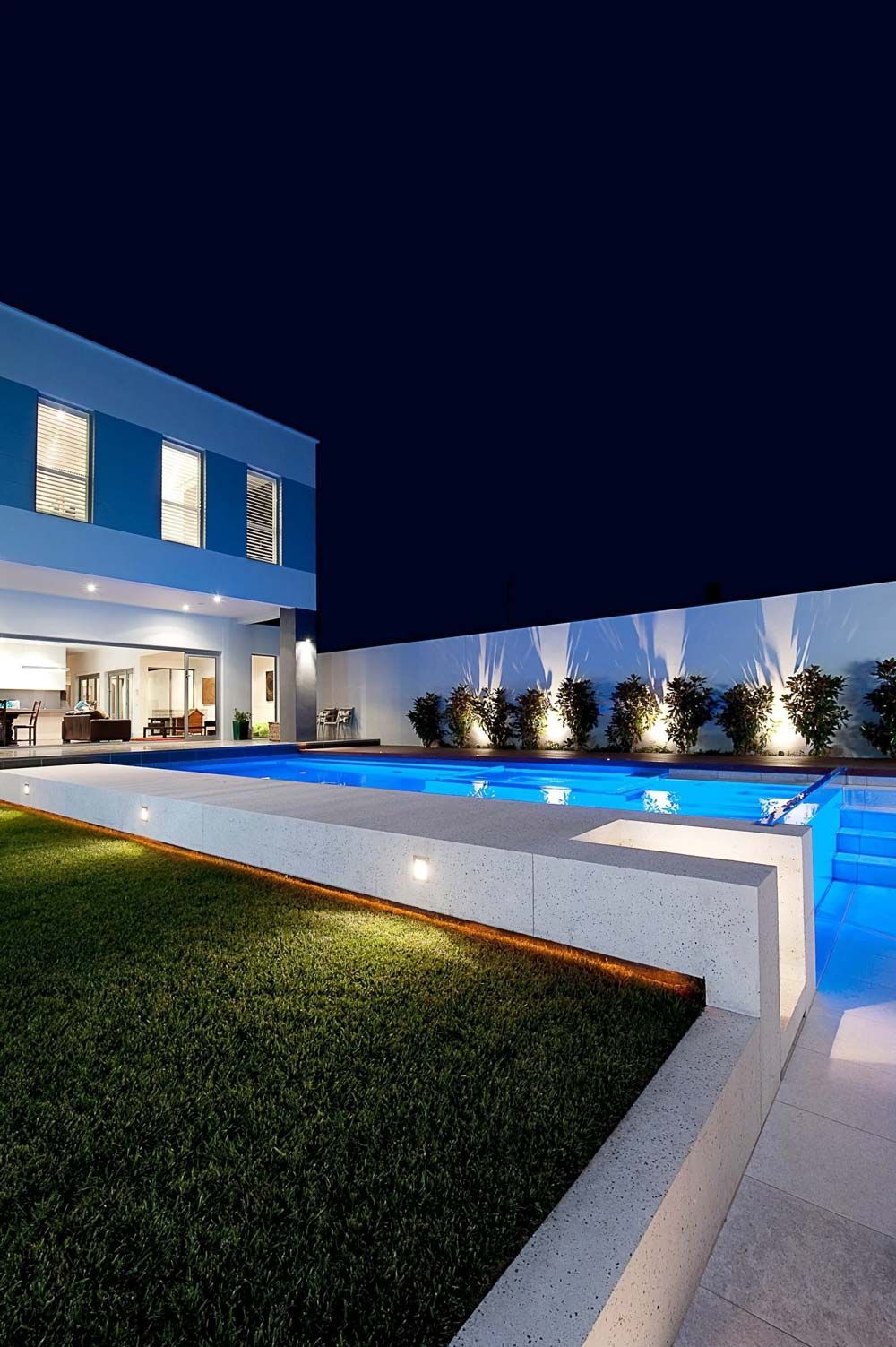 A large swimming pool in front of a house at night — Pool Equipment Installation in Kewarra Beach QLD