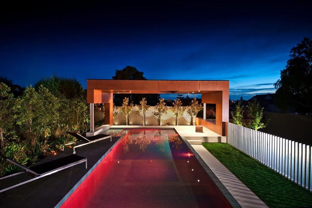 A large swimming pool is lit up at night in front of a house — Pool Equipment Installation in Kewarra Beach QLD