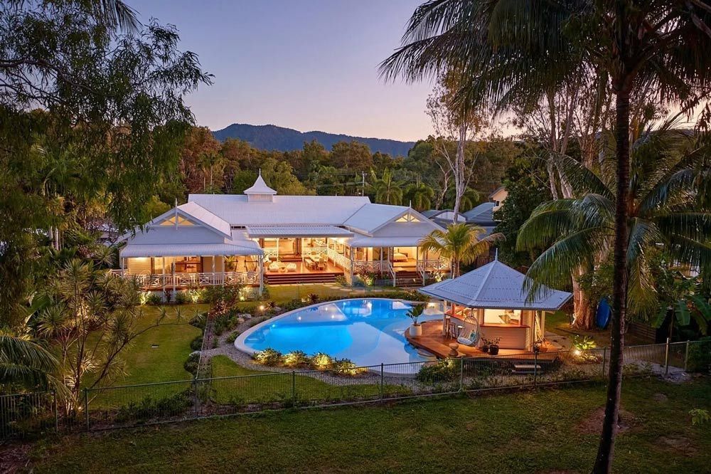 A large house with a swimming pool in the backyard surrounded by palm trees — Pool Shop in Kewarra Beach QLD
