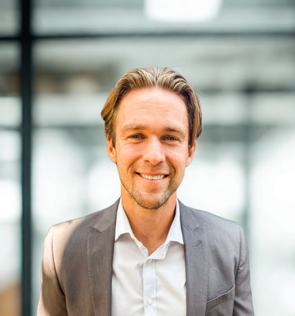A man in a suit and white shirt is smiling for the camera.