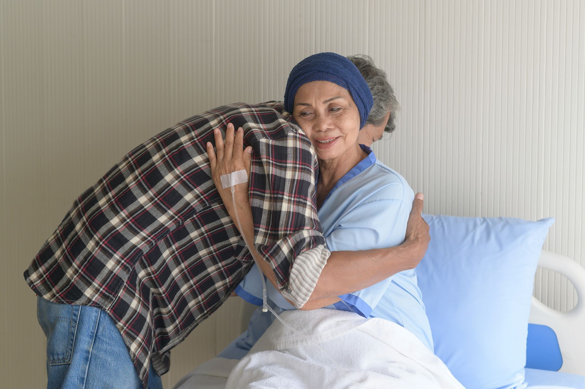 A man is hugging a woman in a hospital bed.