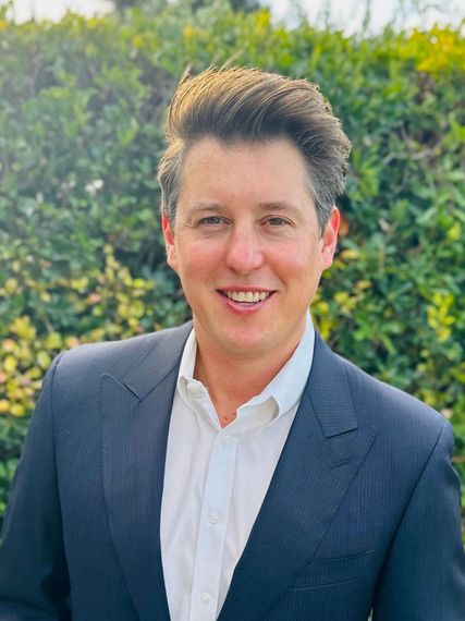 A man in a suit and white shirt is smiling for the camera.