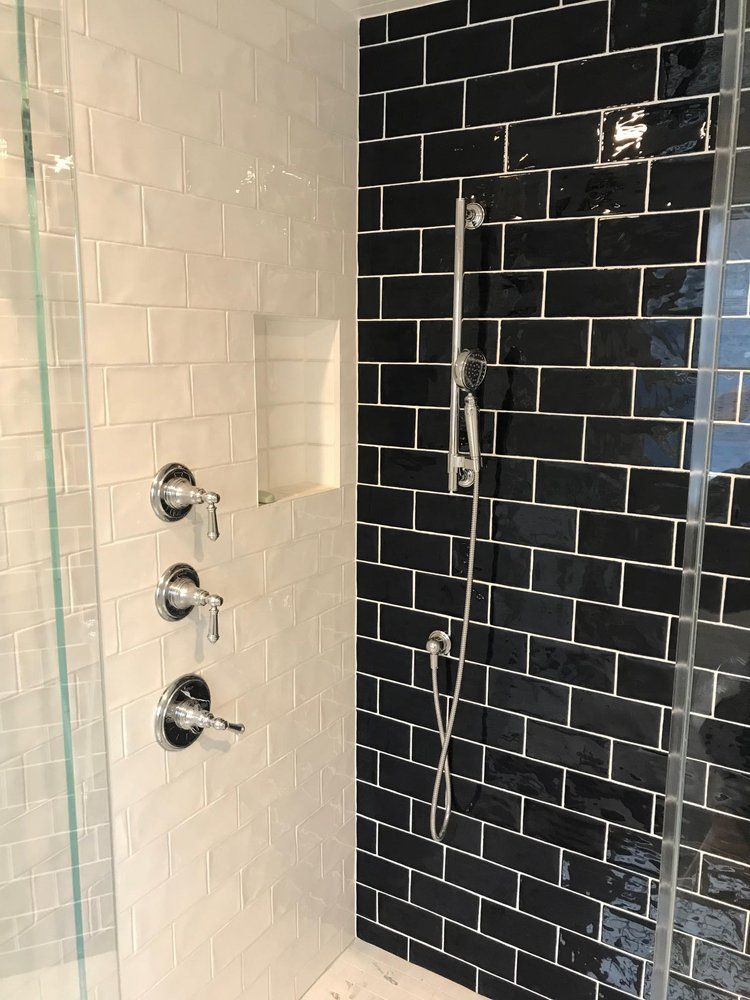 Bathroom shower with black and white tiled walls, chrome fixtures, and glass door.