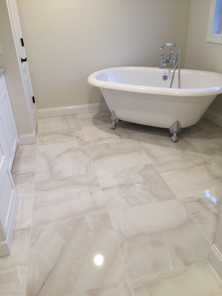 White clawfoot tub in a bathroom with light-colored tile flooring.