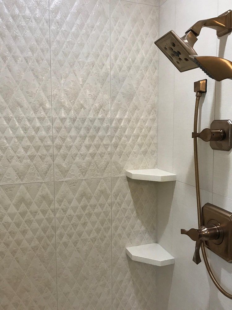 Shower with diamond-patterned wall tiles, bronze fixtures, and white corner shelves.