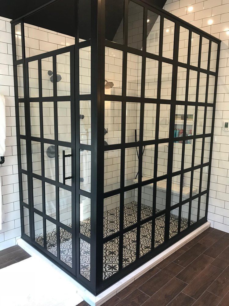 Black-framed glass shower with grid design. White subway tile walls, patterned floor.