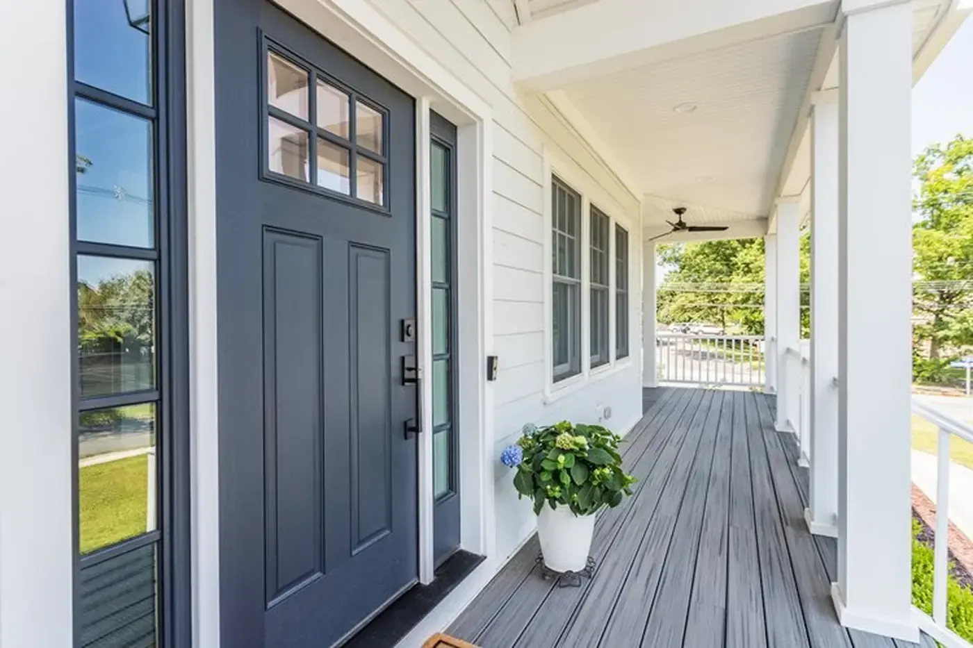 Blue front door with sidelight on a white porch with a gray floor.