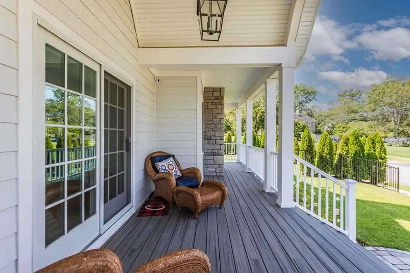 Covered porch with wicker chair, white siding, and french doors.