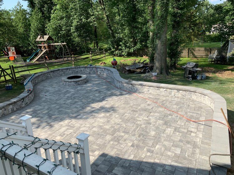Stone patio with built-in fire pit and stone border in a backyard setting.