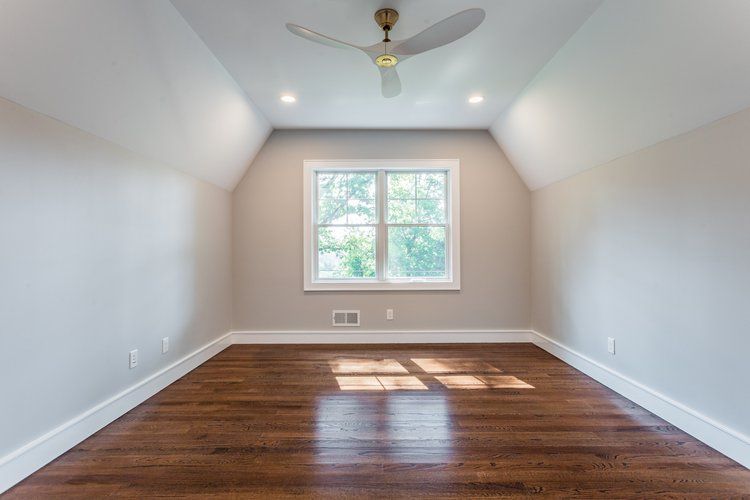 Empty room with hardwood floor, white trim, window, and a ceiling fan.