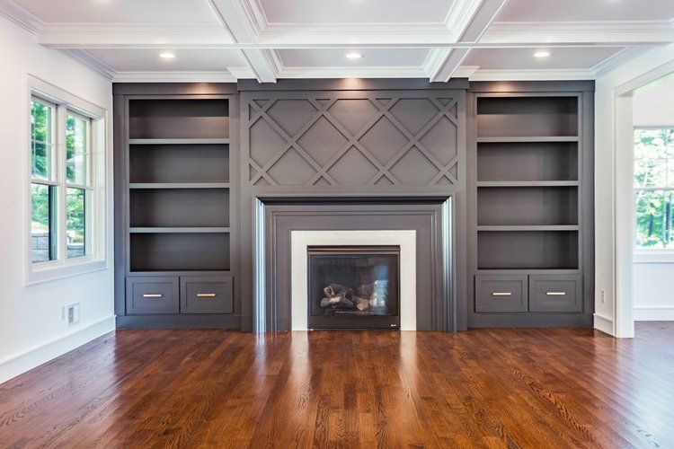 Living room with gray fireplace, bookshelves, and wooden floor.