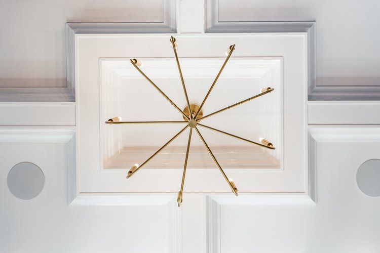 Gold sputnik chandelier hangs from a white paneled ceiling with recessed lighting.
