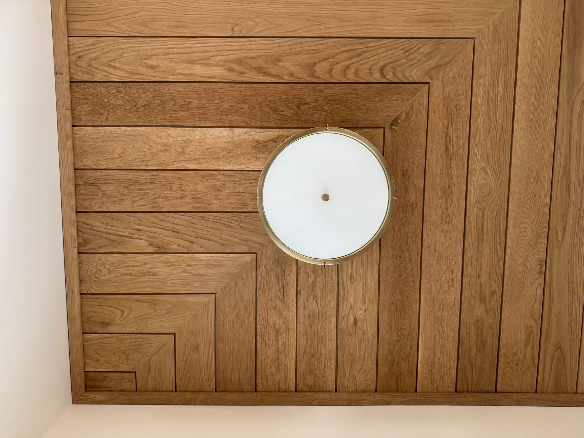 Wooden ceiling with inlaid design, circular light fixture.