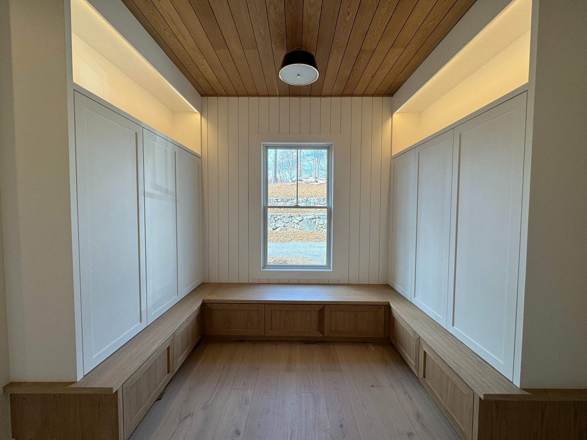Cozy nook with wood ceiling, white walls, built-in storage, and a window.