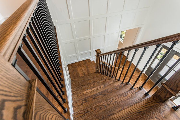 Wooden staircase with black metal balusters, leading downwards.