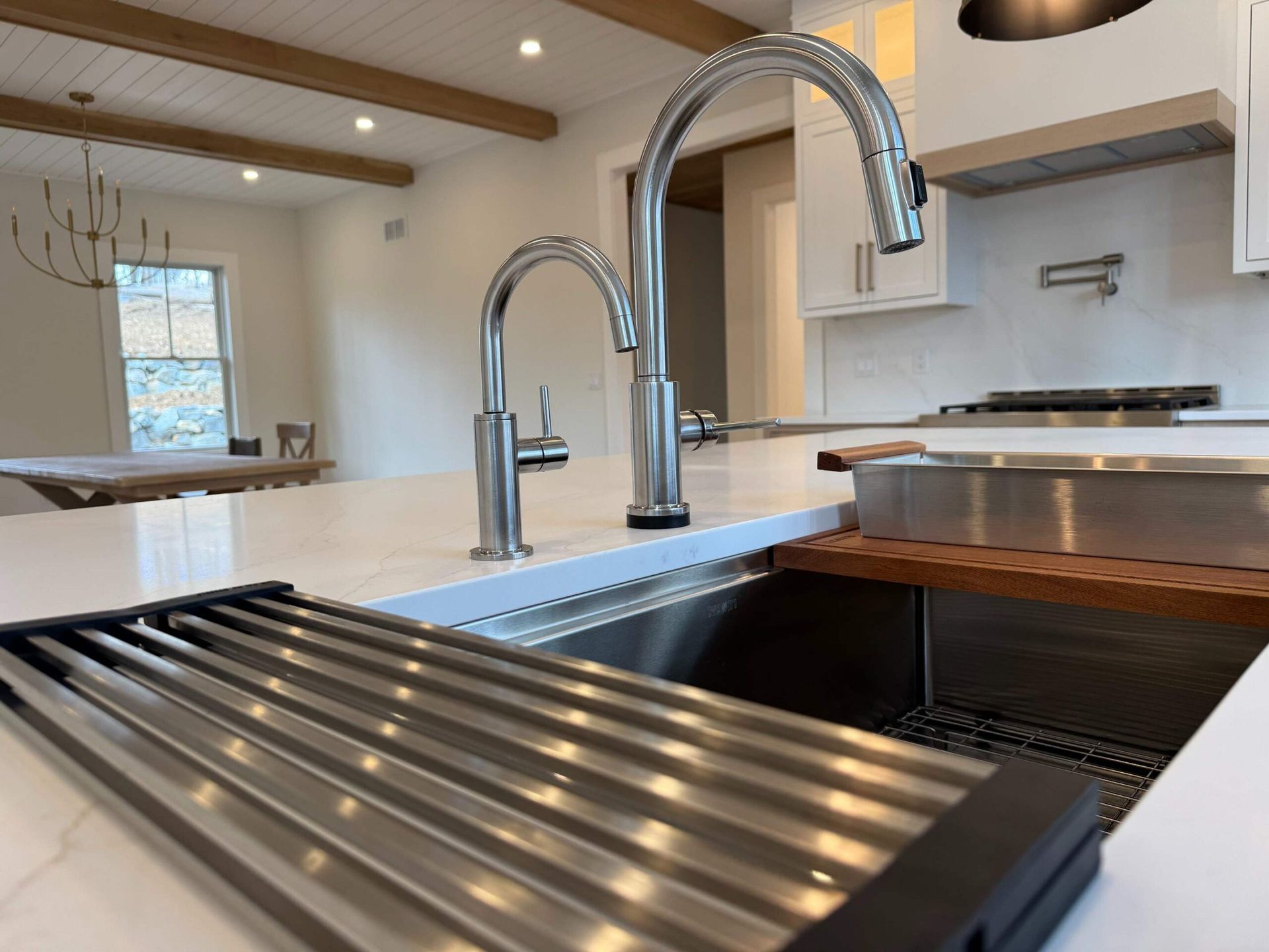 Stainless steel kitchen sink with two chrome faucets, drying rack on the counter.