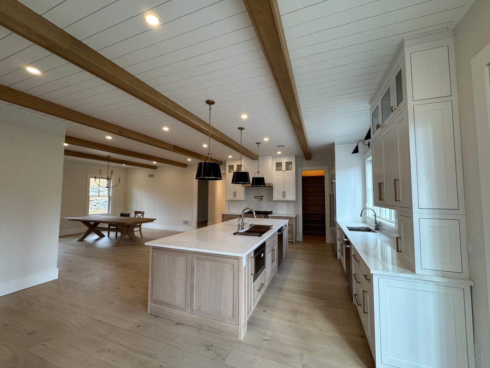 Modern kitchen with light wood floors, white cabinets, and island with stainless steel appliances.