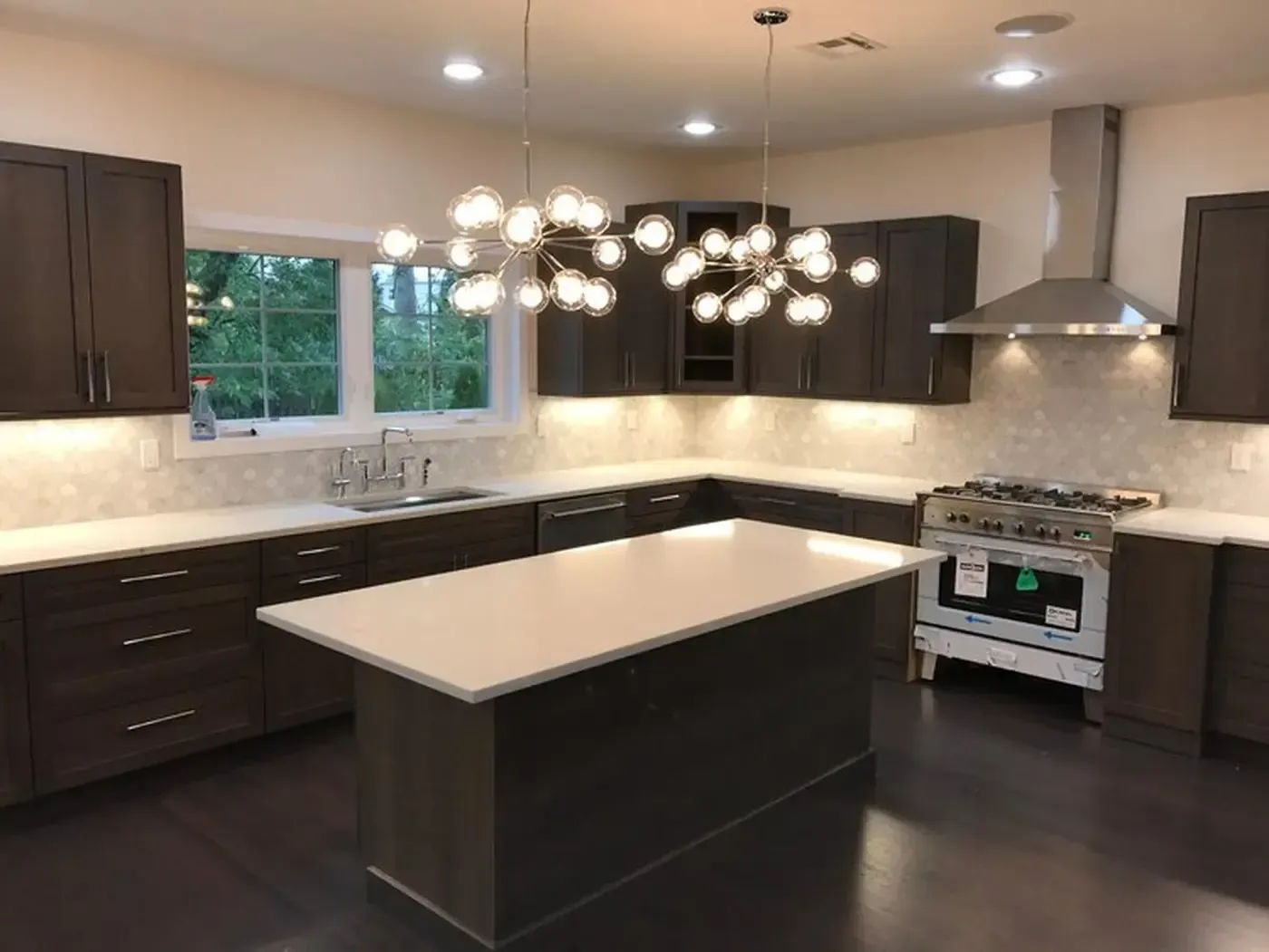 Modern kitchen with dark brown cabinets, white countertops, and a central island.