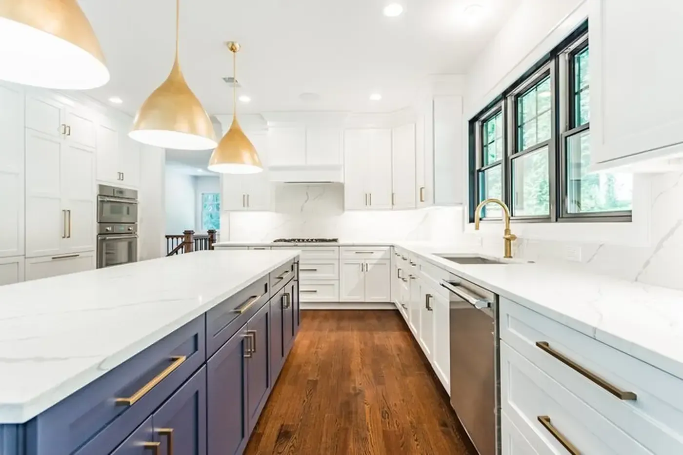Modern kitchen with white cabinets, purple island, wood floor, gold accents, and windows.