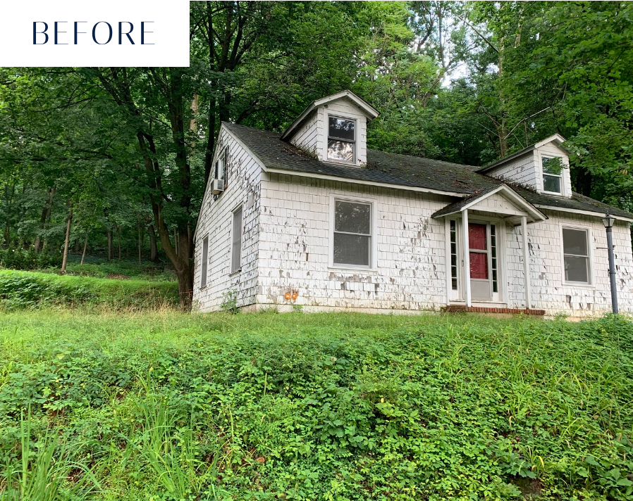 Dilapidated white house with overgrown yard, surrounded by trees.