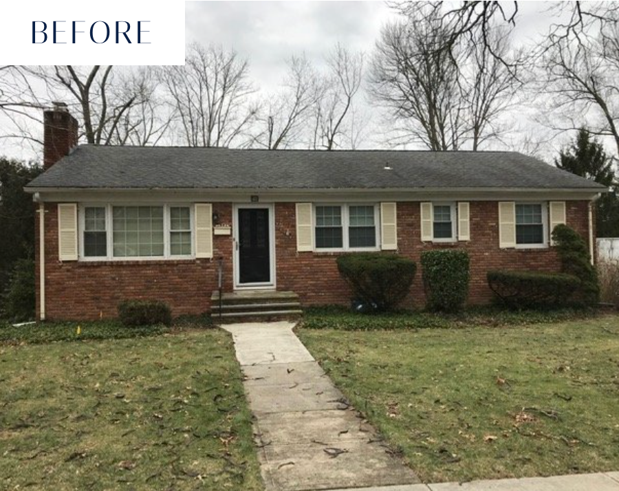 Red brick ranch house with black door, beige shutters, gray roof and walkway; cloudy sky.