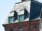 a brick building with a blue roof and green windows .