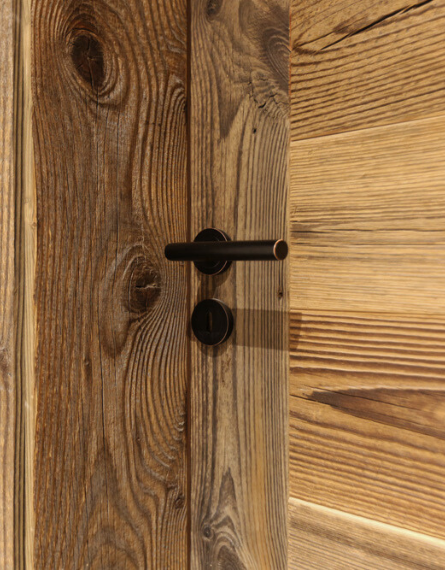 Intérieur en bois avec une table, des chaises, des étagères et une porte vitrée donnant sur une terrasse.