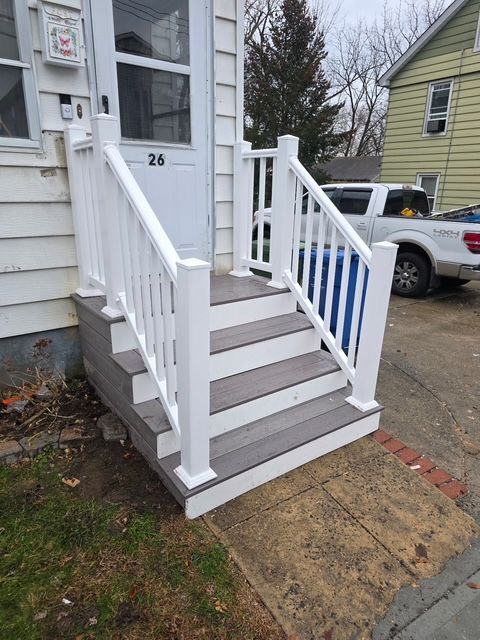White railing and steps leading to a white door with the number 26.