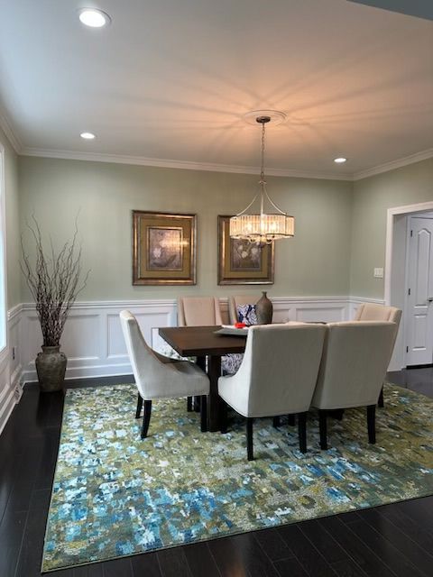 Dining room with a table, chairs, art, rug, and chandelier.