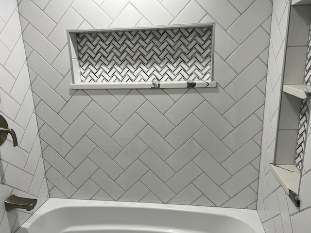 White tiled bathroom with herringbone pattern and decorative niche.