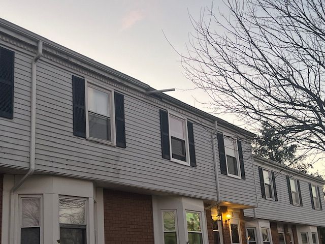Row of townhouses with gray siding, black shutters, and bay windows.