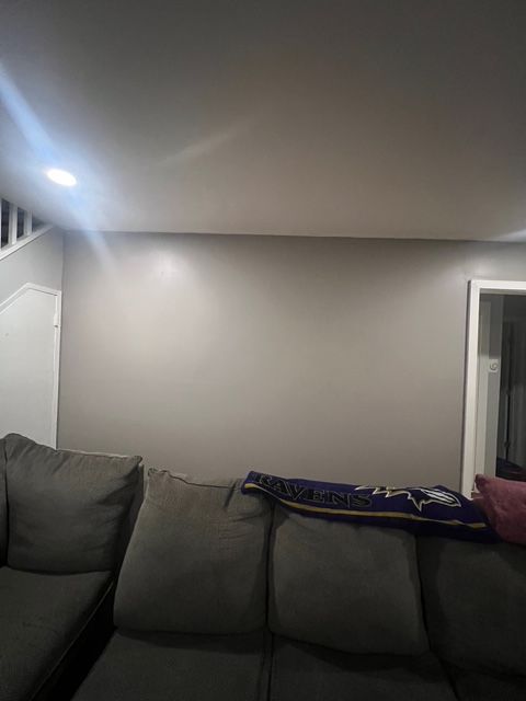 Gray wall above a gray couch with a stairway and a window in the background.