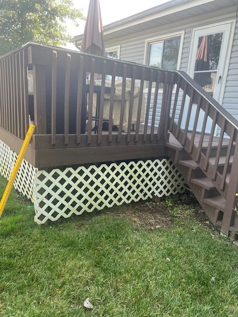 Brown deck with white lattice skirting and stairs leading to a grassy yard.