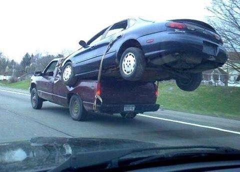 A car is being towed by a truck on the back of it.