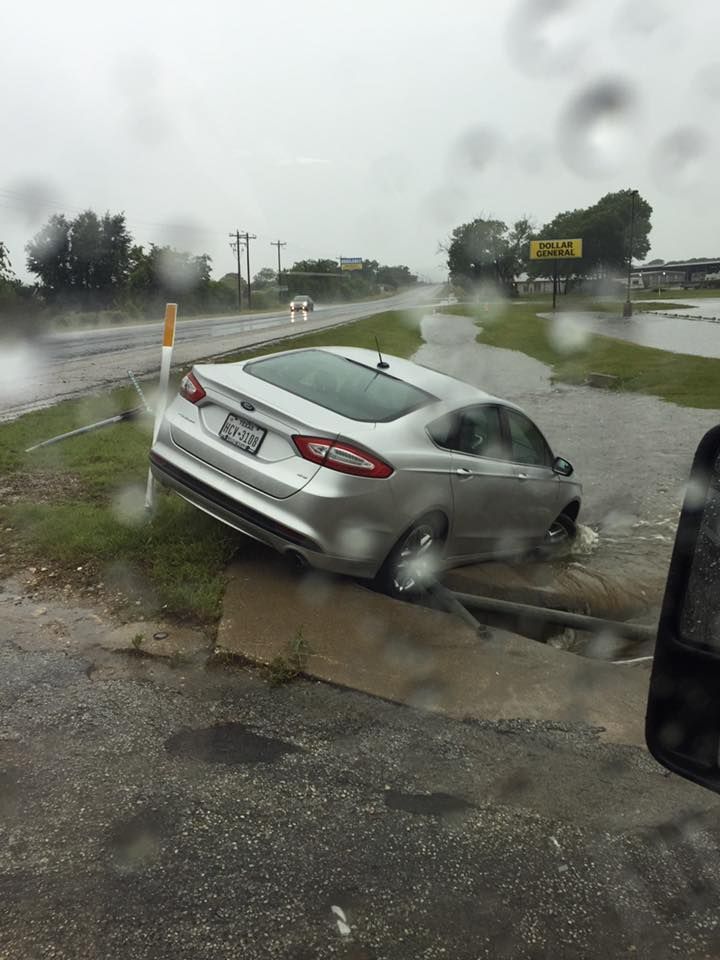 A car is stuck in a puddle of water on the side of the road.