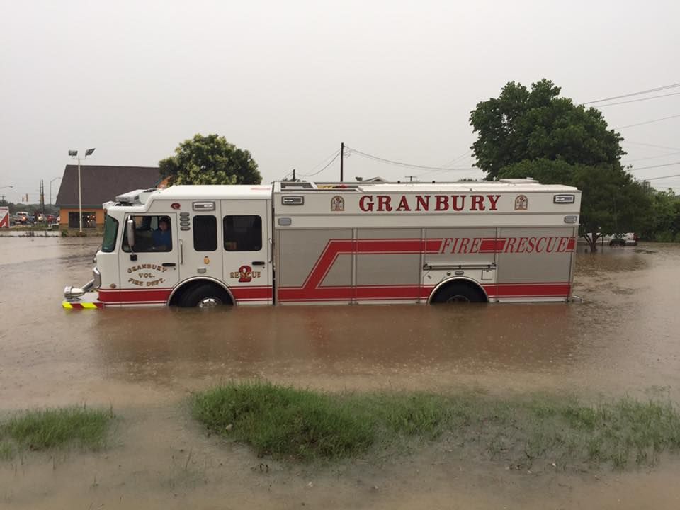 A fire truck from granbury is driving through a flooded area