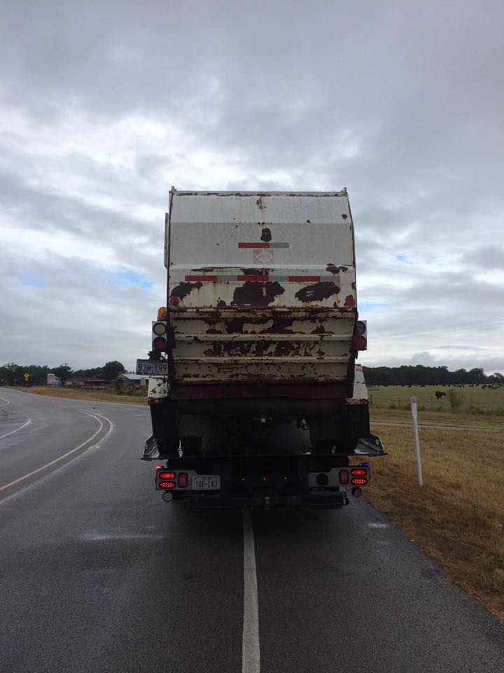 A garbage truck is parked on the side of the road