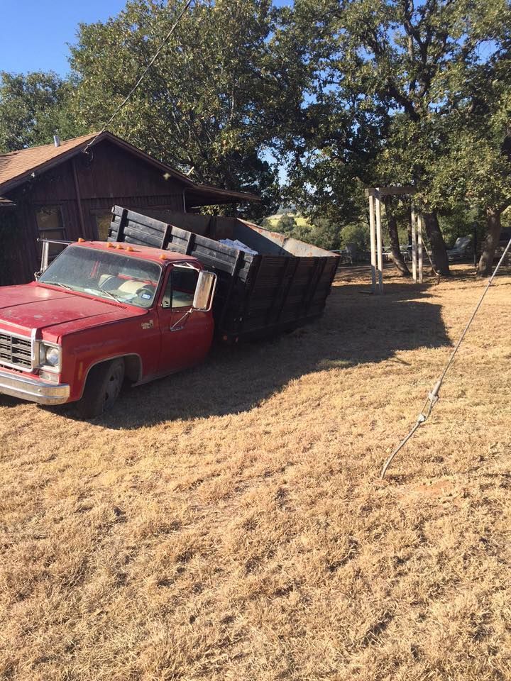 A red truck is parked in a field next to a house.