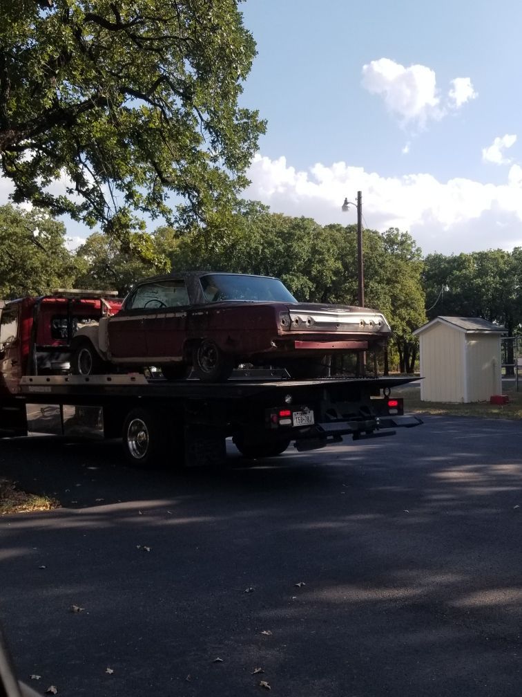 A red car is being towed by a tow truck