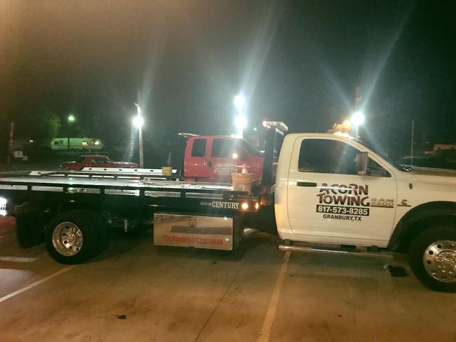 A tow truck is towing a car with a damaged front end.