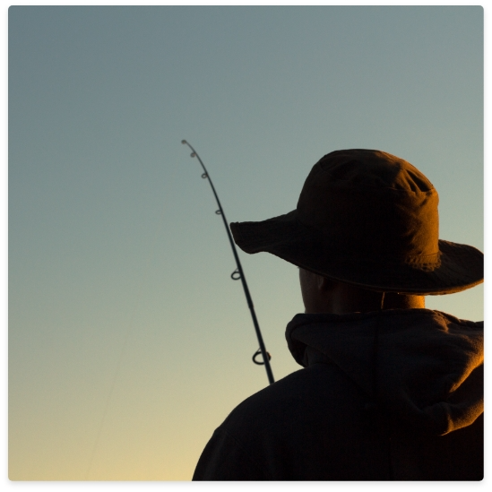 Person fishing with a hat, holding a rod with a sky background.