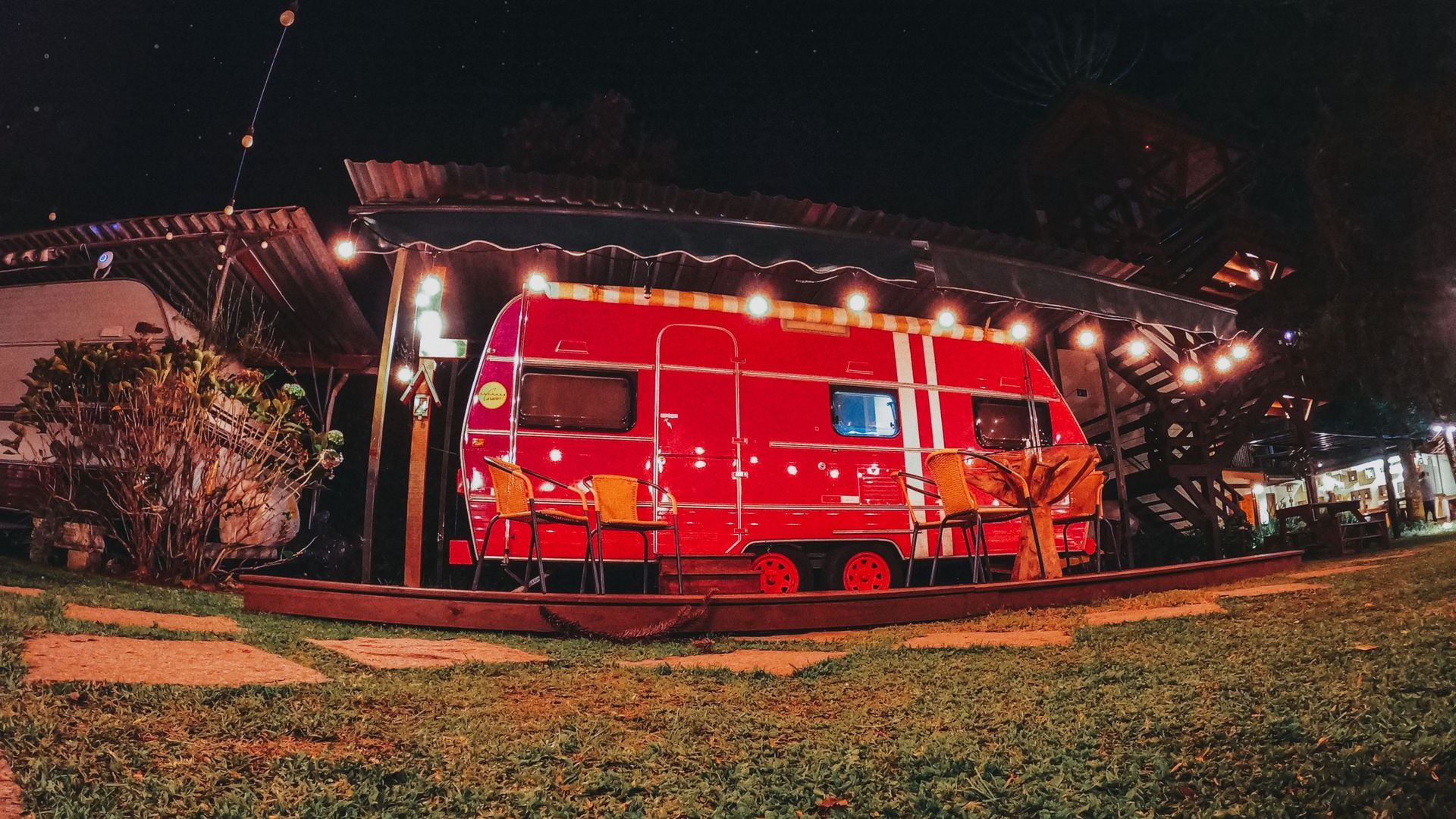 Red food truck lit up at night on a grassy lawn outside a building