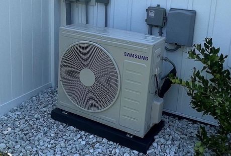 A person is cleaning an air conditioner with their hands.